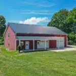 Overhead shot of red barndominium and white farmhouse on a scenic hilltop in Killbuck, Ohio.