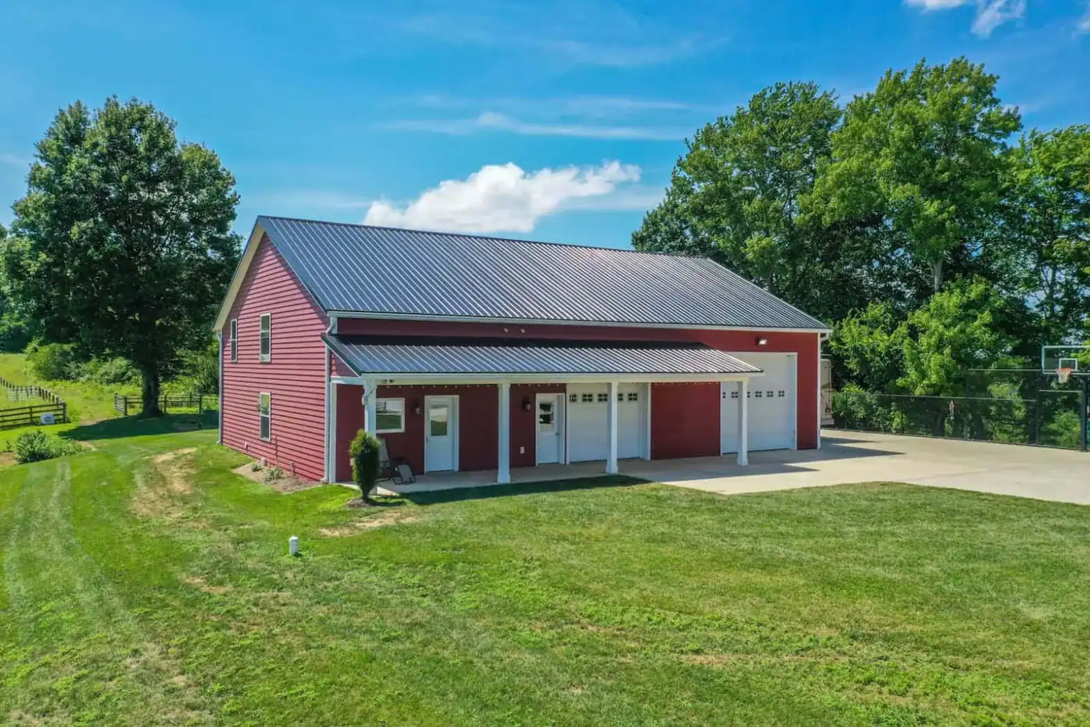 Overhead shot of red barndominium and white farmhouse on a scenic hilltop in Killbuck, Ohio.