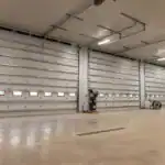 Interior view of the Walhonding Equipment Building in Walhonding, OH, featuring four large insulated overhead garage doors with integrated windows and polished concrete flooring.