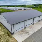 Aerial view of the Walhonding, OH equipment building by Swiss Construction, showcasing the metal roof, multiple overhead doors, and adjacent poultry barns.