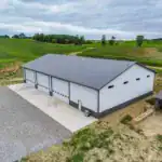 Drone shot of the agricultural equipment garage in Walhonding, OH, highlighting the concrete apron, large bay doors, and scenic rural setting.