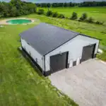 Custom post-frame building in Centerburg, Ohio, featuring symmetrical overhead doors and a rural landscape with private pond.