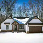 Front elevation of the West Howard Residence, custom-built by Swiss Construction, with timber entry, metal roof, and stone foundation accents.
