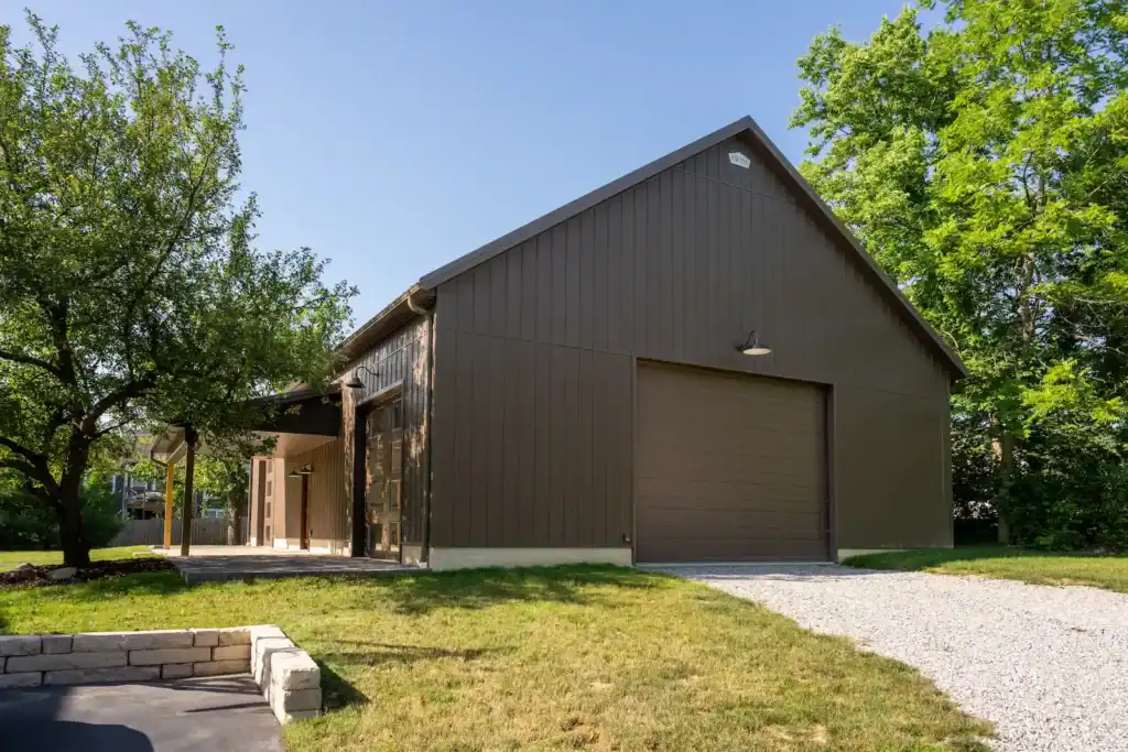 Brown barn-style building by Swiss Construction, with garage door and gravel drive