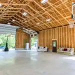 Large barn interior with exposed wood framing, concrete floor, basketball hoop