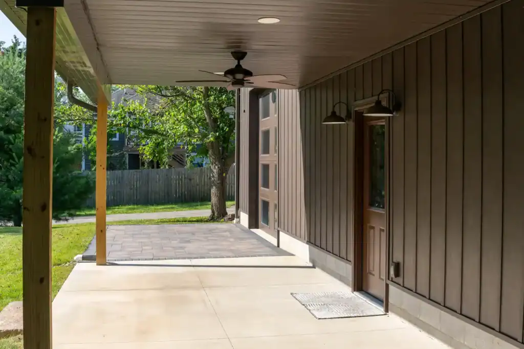 Modern Swiss Construction-designed covered patio with dark siding, concrete floor, and ceiling fan