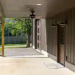 Modern Swiss Construction-designed covered patio with dark siding, concrete floor, and ceiling fan