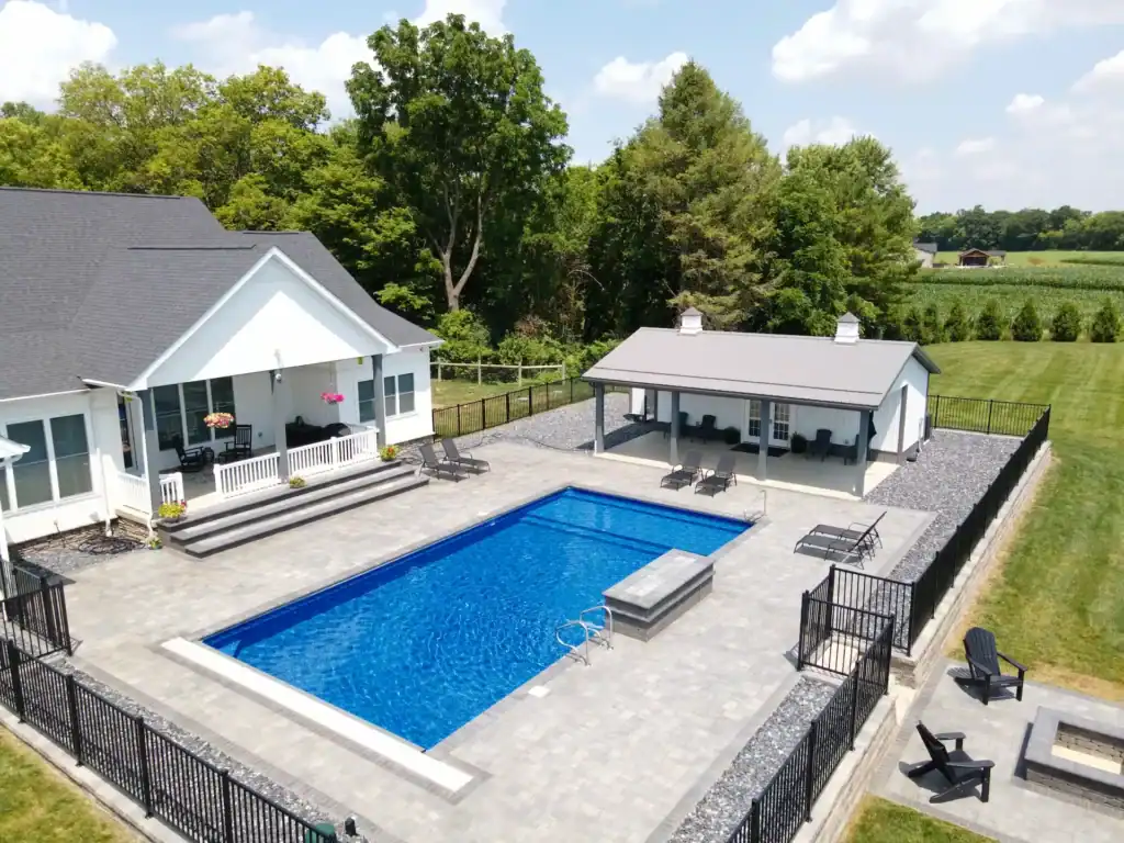 Modern white Swiss Construction pool house, blue pool, patio, and fire pit