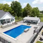 Modern white Swiss Construction pool house, blue pool, patio, and fire pit