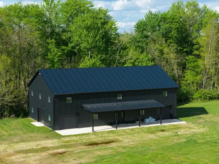 Aerial view of a black metal sports barn in Mount Vernon, Ohio, surrounded by trees and open grass.