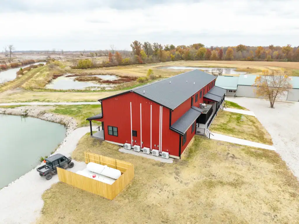 Aerial view of the red two-story Shooting Club lodge overlooking Toussaint River wetlands in Ottawa County, Ohio