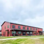 Long red metal elevation of the Shooting Club building by the wetlands