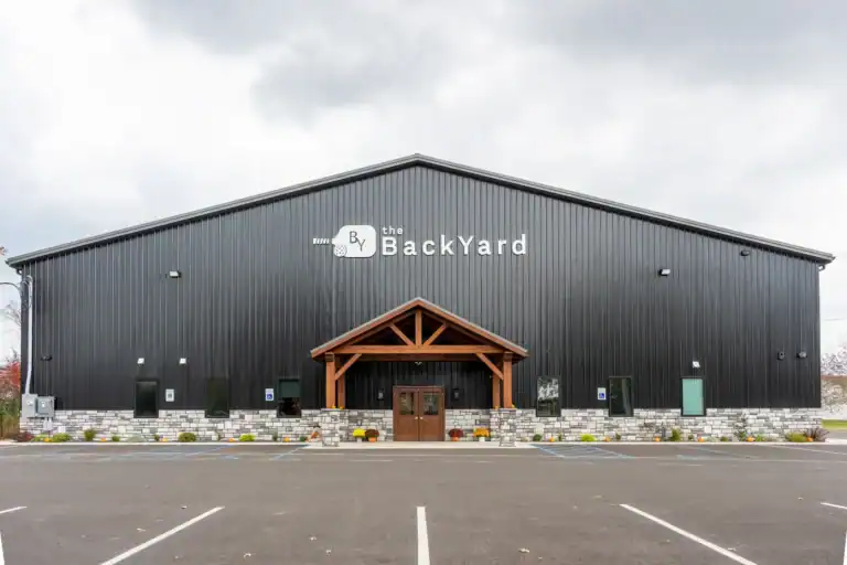 Exterior of The Backyard pole building with timber-framed entrance