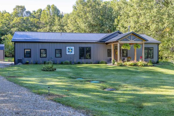 Gray residential pole barn home with metal siding, metal roof and covered front entry in Ohio