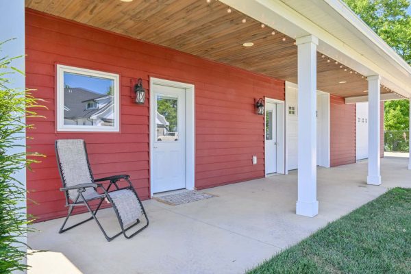 Covered porch entryway with white columns and wood ceiling, part of custom red barndominium in Killbuck, OH.