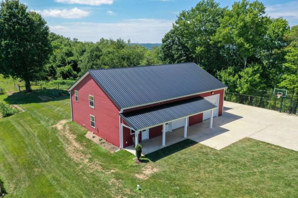 Red residential pole barn garage with metal roof, overhead doors and covered entry in Ohio